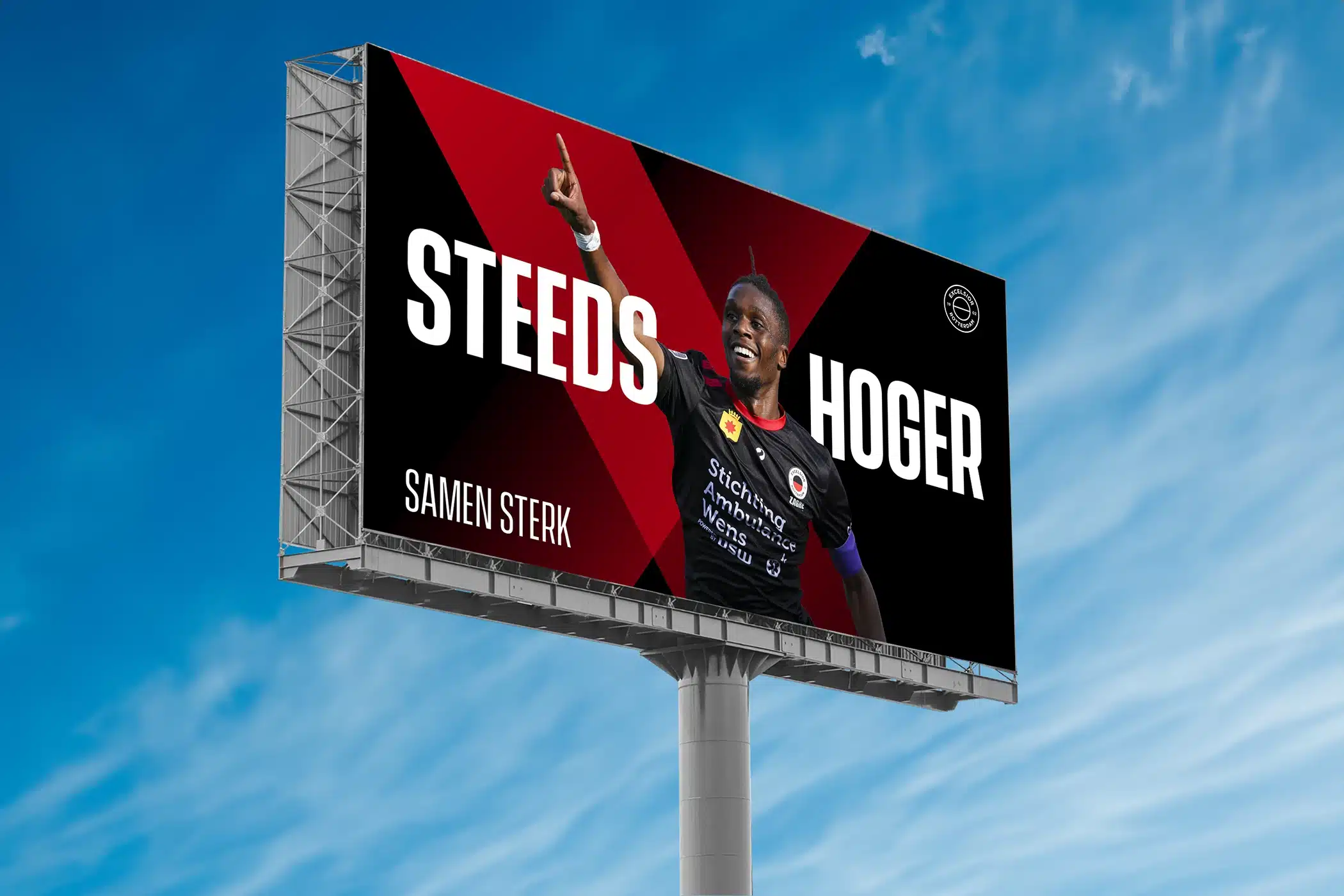 Een groot billboard langs de weg met een afbeelding van een voetballer van Excelsior Rotterdam die juicht, met de tekst "STEEDS HOGER - SAMEN STERK"